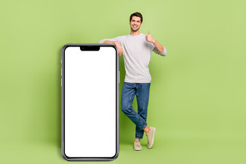 Full size photo of cheerful emotion casual wear man show thumb-up recommend you product isolated on green color background