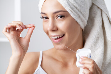 A young woman brushes her teeth with a toothpick and dental floss