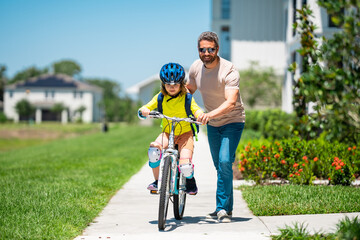 Fathers day. Father and son riding a bike on the road at the fathers day. Concept of friendly family. Parents and children friends. Father and son riding a bike outdoor on summer day. Child first bike