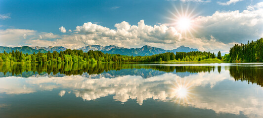 panoramic landscape in region Allgäu at springtime with beautiful lake and alps mountain range in backround