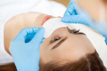 Fototapeta na wymiar Eyelash extension procedure, master fake long lashes beautiful female eyes.