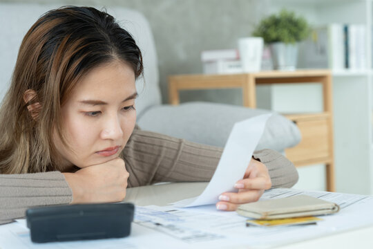 Stressed and headache asian woman with large bills or invoices no money to pay to expenses and credit card debt. shortage, Financial problems, mortgage, loan, bankruptcy, bankrupt, poor, empty wallet.