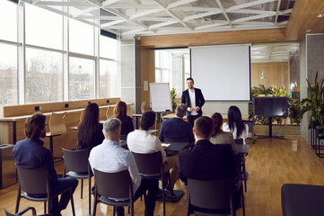 Businessman giving report or presentation to business colleagues. Professional coach consulting, training, explaining strategy to interested people, giving educational workshop in conference room