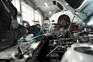 Close up of mechanic's hands repairing car engine in car service