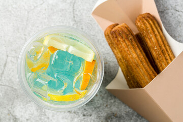 Bubble tea with churros next to it on gray stone background