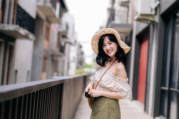 Happy youth asian woman with camera travels street city trip on leisure weekend. Young hipster female tourist sightseeing summer urban Bangkok destination. Asia summer tourism concept.