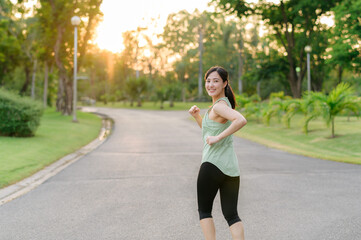 Fit Asian young woman jogging in park smiling happy running and enjoying a healthy outdoor lifestyle. Female jogger. Fitness runner girl in public park. healthy lifestyle and wellness being concept