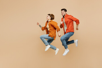 Full body side view young couple two friends family man woman wearing casual clothes together jump...