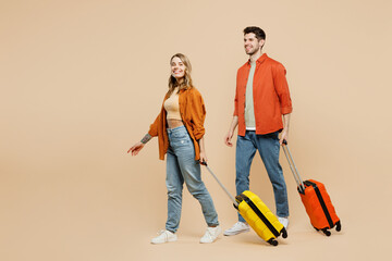 Traveler fun couple two friend family man woman wear casual clothes hold suitcase isolated on plain beige background Tourist travel abroad in free spare time getaway Air flight trip journey concept.