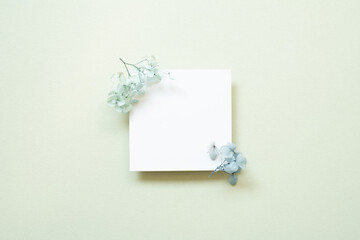 White memo card with blue flower on mint background. top view, copy space