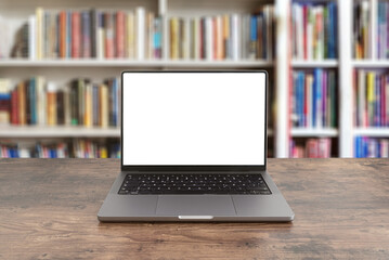 modern laptop computer with blank screen on wooden table against bookshelves filled with books