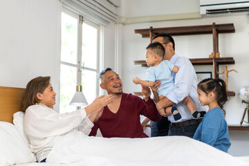 Obraz premium Portrait of happy love asian grandfather with grandmother playing with asian baby and little cute girl on bed.Big family love with their laughing grandparents smiling together.Family and togetherness