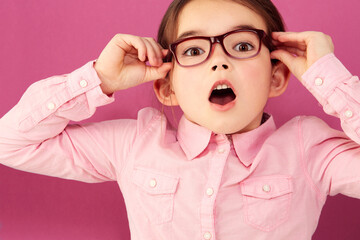 Portrait, shocked and girl child with glasses in studio isolated on a pink background. Kid, nerd and face of surprised person, wow or omg, emoji or reaction to unexpected news, announcement or secret