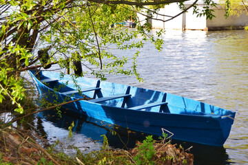 An old wooden boat on the river under the shade of trees