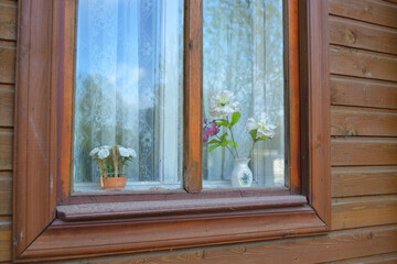 An old wooden window with a flower in a vase.
