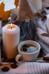 Obraz na płótnie Canvas Thanksgiving and Hello Fall Halloween concept Celebrating autumn holidays at cozy home on the windowsill Hygge aesthetic atmosphere Autumn leaves gnome, spices and candle on knitted white sweater in