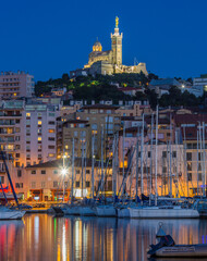 The harbor of Marseille at night. Looking towards the Cathedral de Notre-Dame-de-la-Garde high on a hill overlooking the city. Cote d'Azur in the South of France.