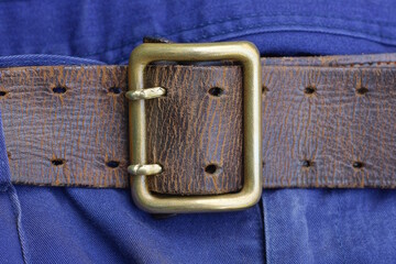 one old brown army leather belt with copper buckle in fabric blue trousers