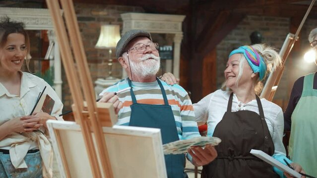 Happy old retired couple in painting art class with a teacher