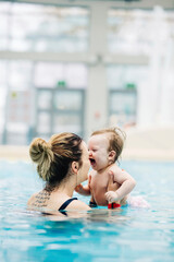 Mother with her baby daughter swim in the pool in waterpark