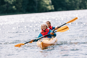 Fototapeta na wymiar Happy senior active couple kayaking on lake