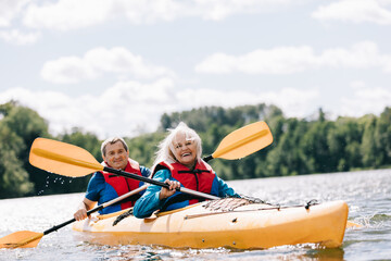 Happy senior active couple kayaking on lake - obrazy, fototapety, plakaty