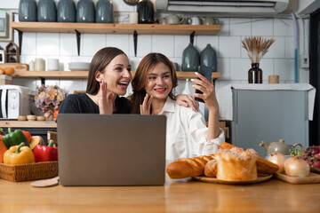 Happy teenage girls making or video calling while resting in the kitchen