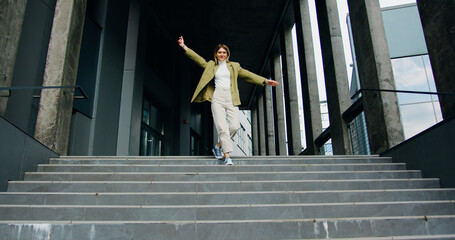Happy playful young woman actively dancing while walking down the stairs.