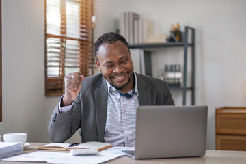Fototapeta na wymiar Happy excited successful businessman triumphing in office, Portrait of a cheerful happy business man sitting at the laptop in office
