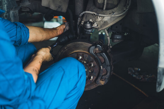 For garage automobiles, brand-new brake discs. A mechanic is working in the garage replacing new tires and fixing brakes.