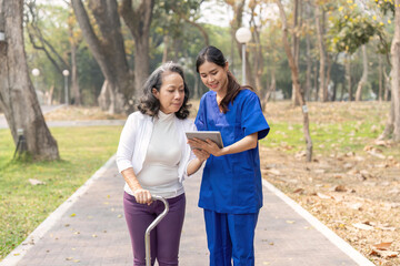 Female nurse showing medical report to senior woman on digital tablet at hospital park