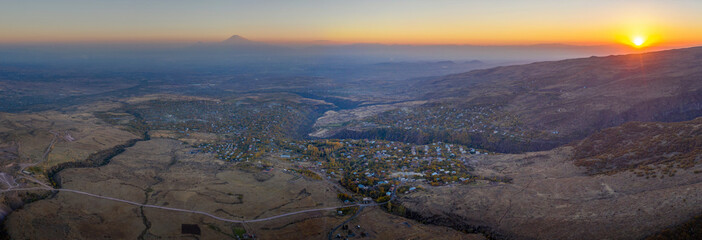 Panoramic aerial view of Byurakan village, Amberd canyon and Mount Ararat at sunset. Armenia.