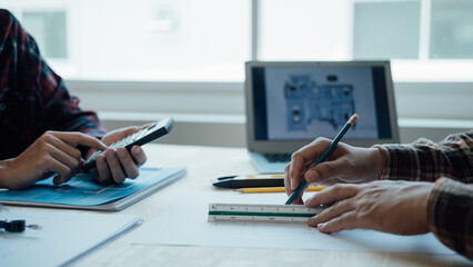Architecture Interior designer working with building apartment plans blueprints on desk table at construction site office, closeup.