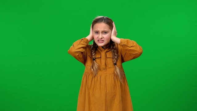 Unsatisfied teen girl covering ears with hands hearing unpleasant disturbing sound looking at camera. Medium shot portrait of dissatisfied Caucasian teenager posing at chroma key background