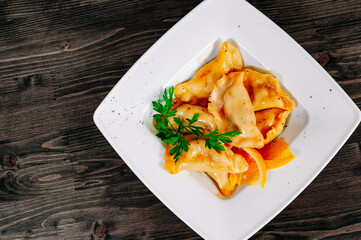Meat dumplings - russian pelmeni, ravioli with meat on plate on a wooden background