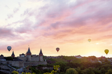 Beautiful sunset summer landscape with ancient castle and balloons in the sky. Kamianets-podilskyi, Ukraine.