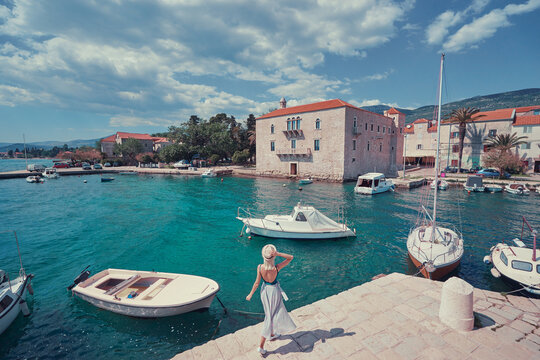 Tourism concept. Young traveling woman enjoying the view of Kastel Castle walking near the sea on Croatian coast.