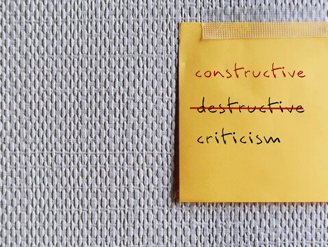 Note stick on copy space office wallpaper with handwritten DESTRUCTIVE CRITICISM, changed to CONSTRUCTIVE CRITICISM - means to shift focus on negative to be on building up other person