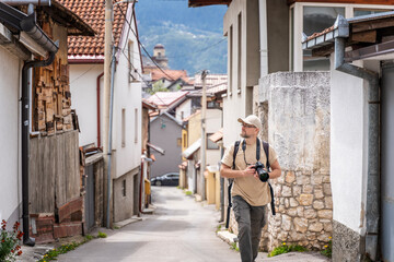 Young adult caucasian male traveler with backpack and camera walking through old streets in sarajevo, traveling to Bosnia and Balkan countries