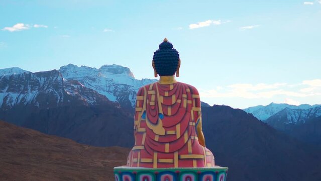 Rear view shot of Langza Buddha statue in front of the Snow covered Himalayan mountains at Langza village in Spiti Valley, Himachal Pradesh, India. Statue of Buddha facing the snowy Himalayas in India
