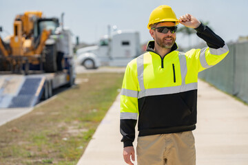 Builder with hardhat helmet on construction site. Construction engineer worker in builder uniform near construction building. Portrait of builder in a construction site build new house.