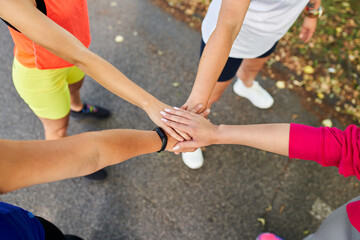 Group of female runners joining hands after outdoor workout