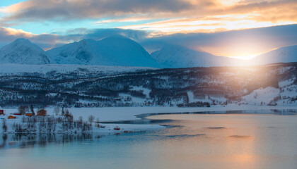 Beautiful winter landscape with red  house and red cabin in the background snowy mountains - Tromso, Norway