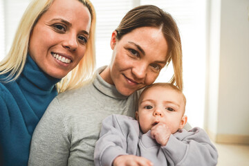 Mothers gay couple taking selfie with their baby son at home - Family, lgbt and love concept - Main focus on right mother eye