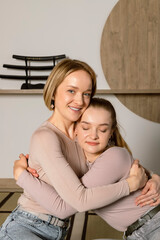 Portrait of Beautiful blonde twin sisters hugging or embracing and smiling, Japanese style studio at the background. Sisterly love, Twins bond and connection.