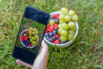 Zdjęcie miski pełnej owoców robione smartfonem  - obrazy, fototapety, plakaty
