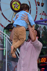 Man throwing boy into the air at a park, Children's Day, Father's Day, father and son, father and child, father at an indoor amusement park, family fun, joyful childhood moment