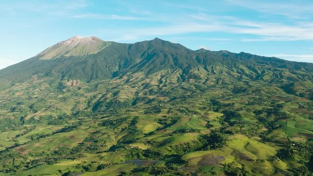Aerial drone of farmland with plantings against a background of mountains and blue sky. Canlaon volcano. Negros, Philippines