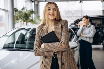 Woman choosing a car with dealership in a car showroom