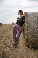 Naklejka na ściany i meble Outdoor fashion portrait of stylish young woman in autumn wheat field after harvest